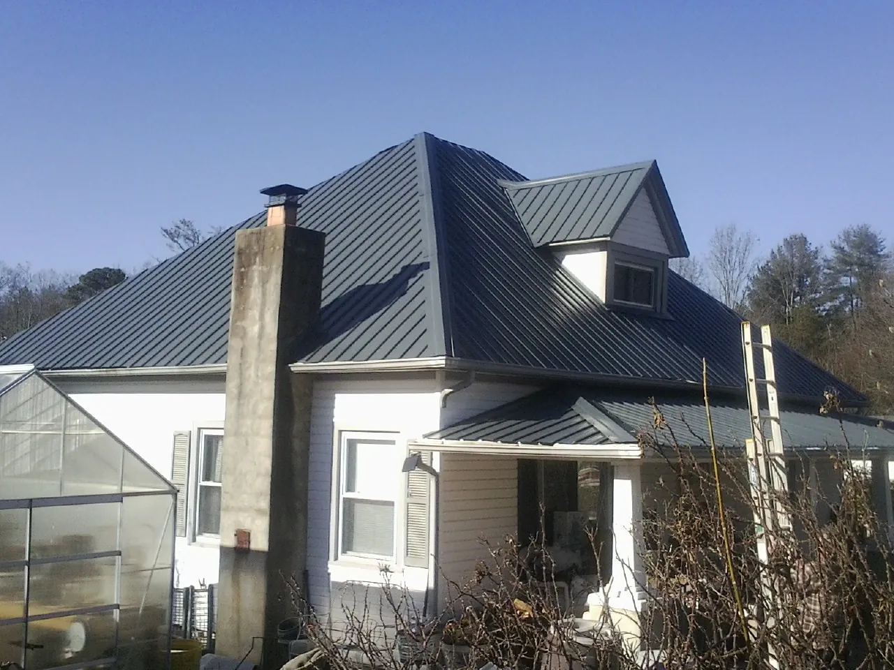 Dark blue standing seam metal roof on a white farmhouse with dormer — Slate & Tile Roof Repair by Roofing Brothers in New Providence